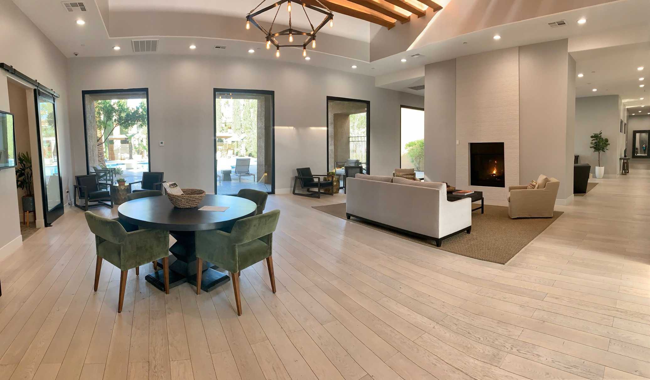 Ritiro Apartments clubhouse lounge with a fireplace, seating area and floor-to-ceiling windows overlooking the pool